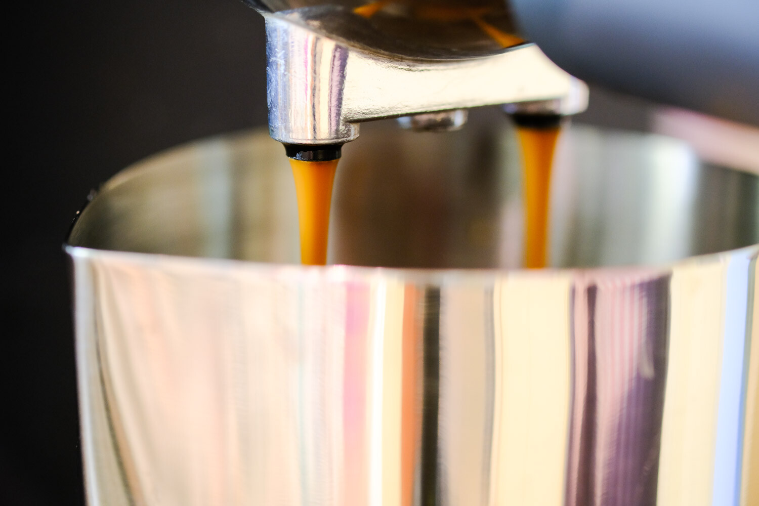 Espresso pouring into a metal jug